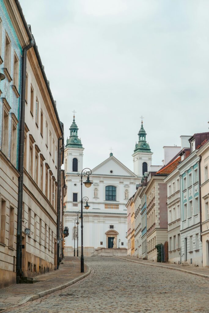 A picturesque view of a historic church on a cobblestone street in Warsaw, Poland.