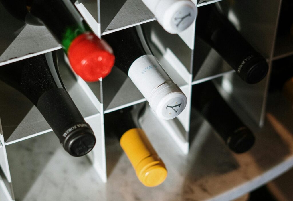 Various wine bottles stored in a geometric wine rack, offering a close-up of bottle tops with a mix of colors.