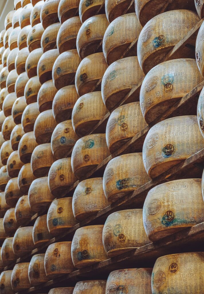 Rows of aged Parmesan wheels on wooden racks in a traditional Italian cheese factory.
