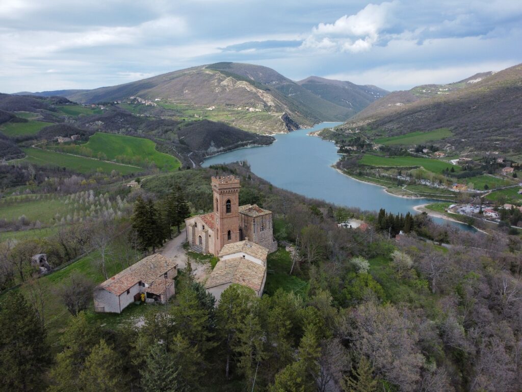 Scenic aerial view of a historic castle on a hill overlooking a beautiful lake and lush valley.